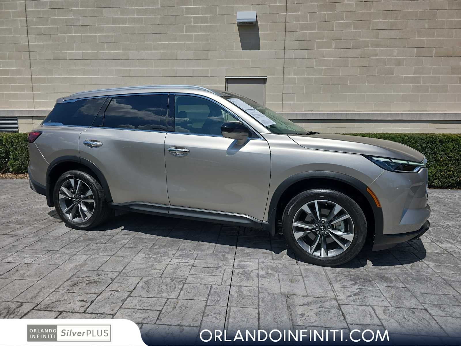 2025 INFINITI QX60 LUXE in Warm Titanium — front three-quarter view